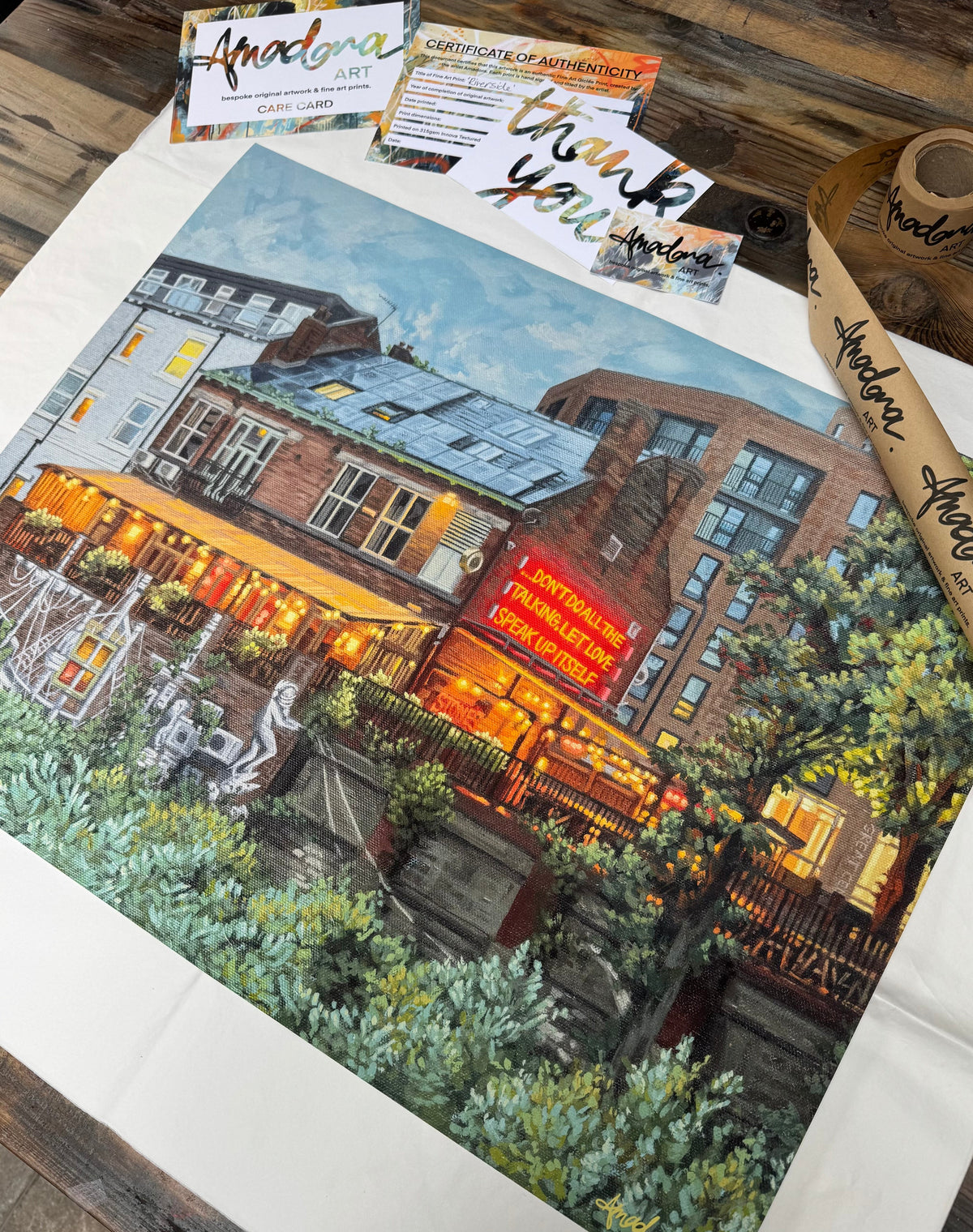 Painting a cosy building with neon sign reading ‘Don’t Do All The Talking, Let Love Speak Up Itself’.  A Thank You card, Certificate of Authenticity, and Amadora’s branding in the background.